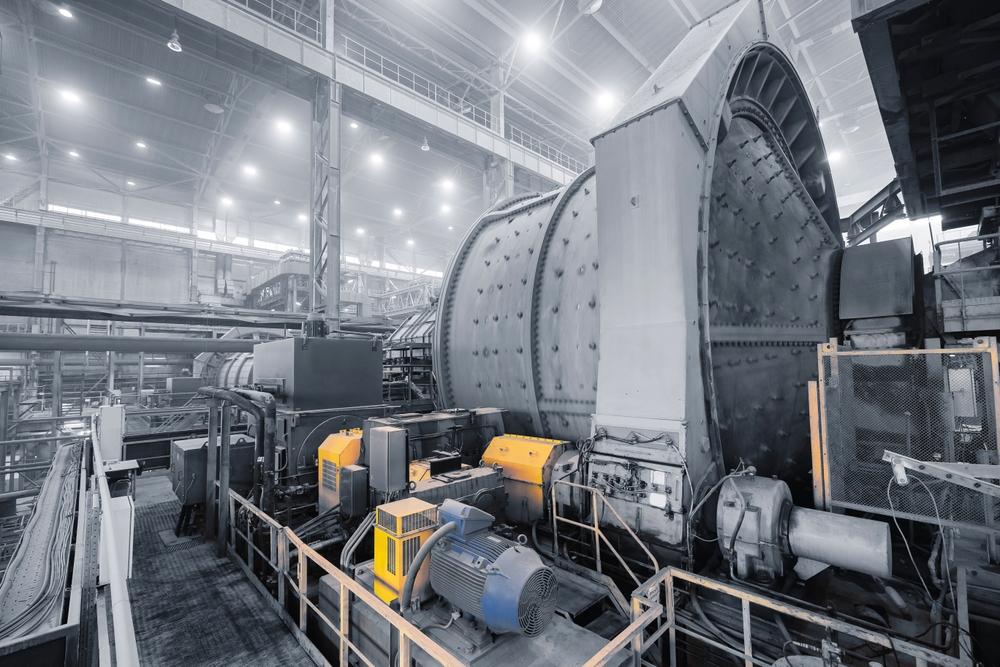 Industrial ball mill with heavy-duty electric motors and machinery inside a large-scale minerals processing plant