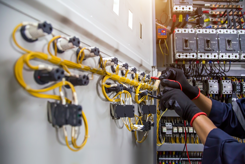 Industrial electrician wiring connections inside an electrical control panel cabinet